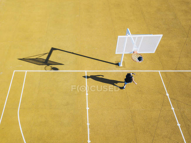 Aerial view of man playing basketball on yellow outdoor court. — Stock Photo