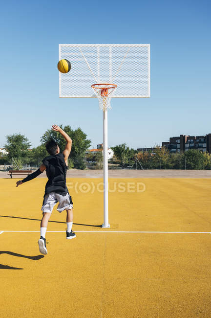 Young man playing on basketball court outdoors. — Stock Photo