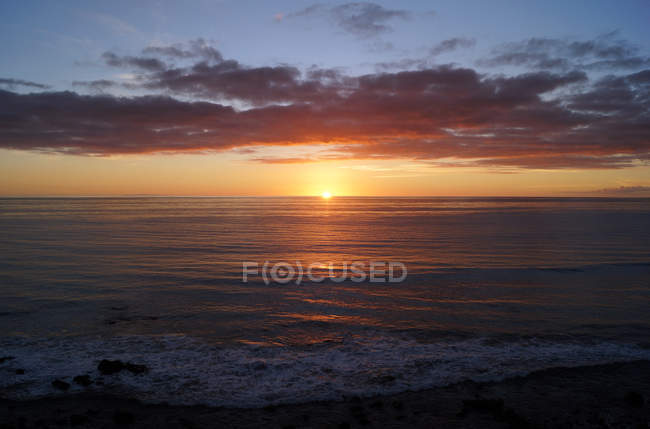 Vista para a praia arenosa e rochosa e para o oceano em luzes do pôr do sol na ilha canária — Fotografia de Stock