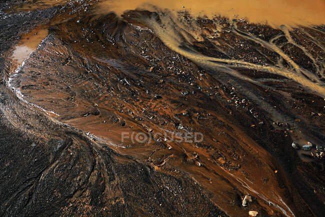 De arriba abajo el suelo oscuro abstracto con el charco sucio y el agua oxidada que gotea fluye. - foto de stock