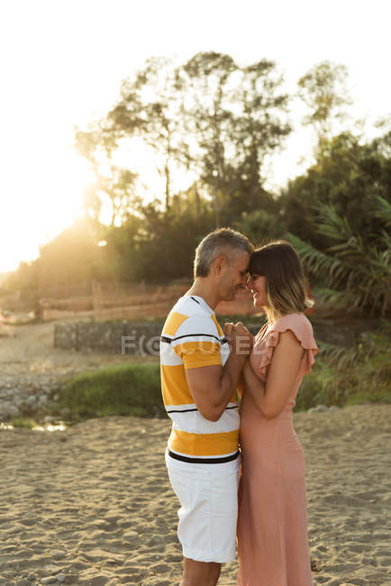 Side view of adult man and woman holding hands and looking at each other with happy smile outdoors — Stock Photo