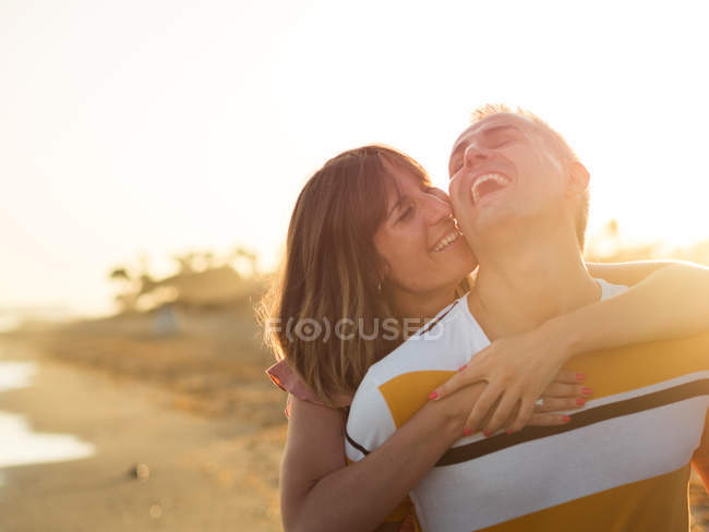 Alegre masculino dando piggyback passeio para sorrir fêmea no resort — Fotografia de Stock