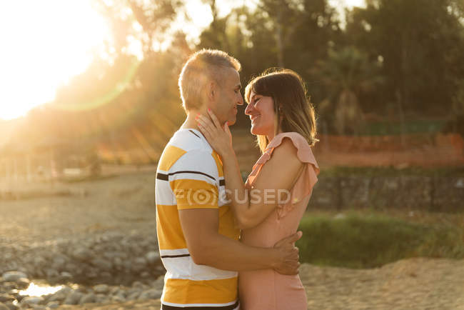Пара смотрит друг на друга с счастливой улыбкой в подсветке — стоковое фото