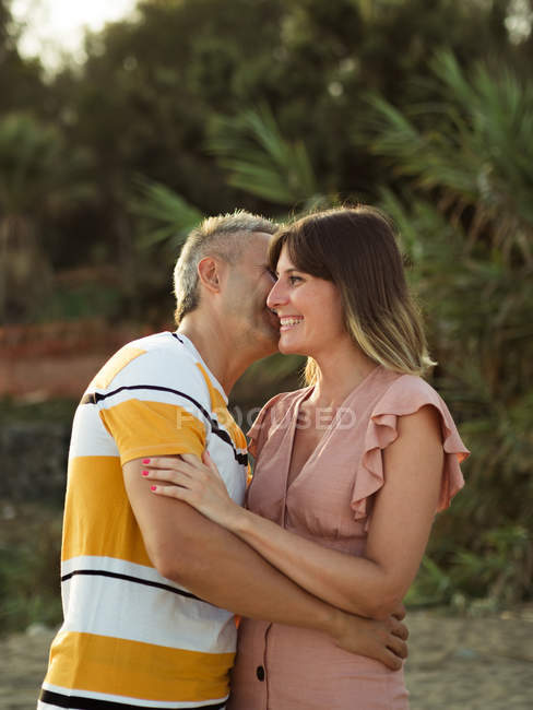 Mann umarmt und küsst erwachsene Frau mit glücklichem Lächeln — Stockfoto