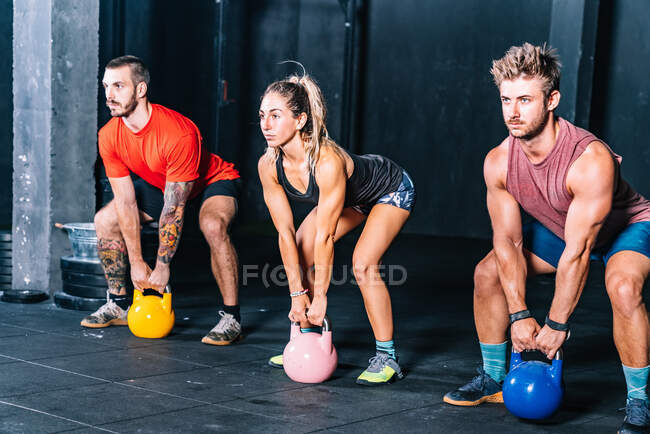 Athletic strong fellows doing workout with weight in gym - foto de stock