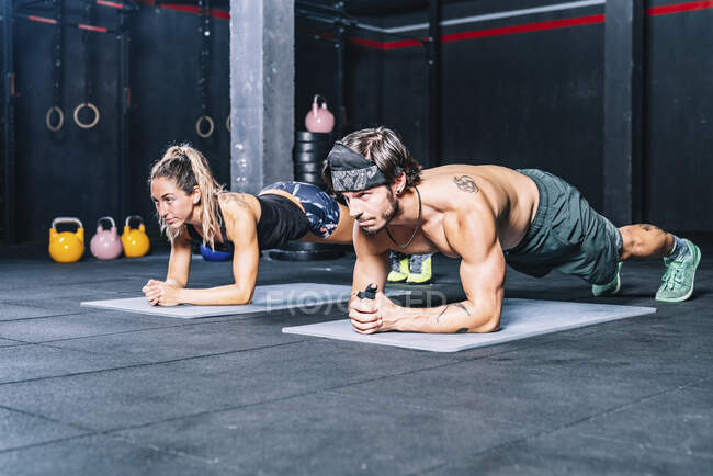 Muscular fellows doing abs in contemporary health club - foto de stock