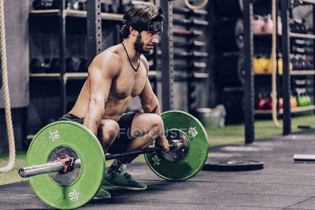 Homme fort et athlétique faisant l'entraînement d'haltère dans la salle de gym moderne — Photo de stock