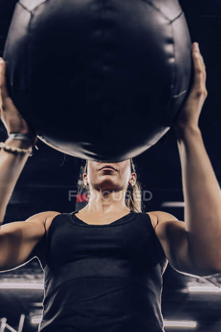 From below athletic female in sportswear training with fitball in health club — Stock Photo