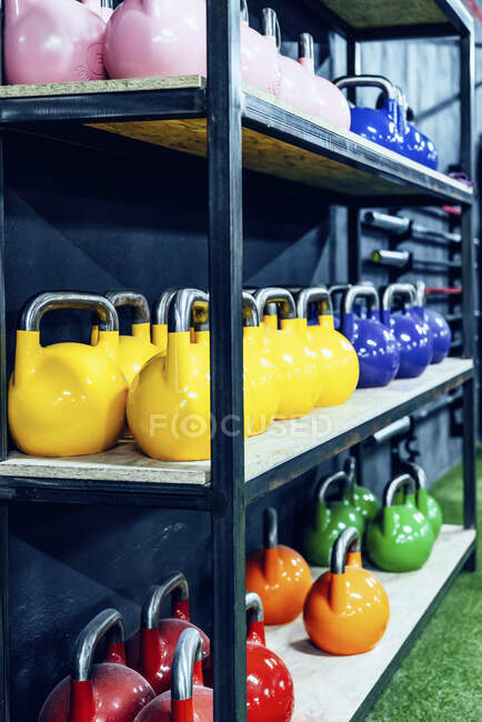 Conjunto de kettlebells coloridos nas prateleiras no moderno health club — Fotografia de Stock