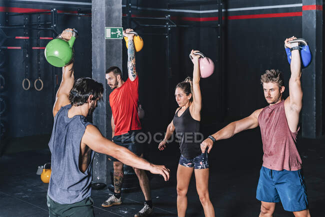 Athletic strong fellows doing workout with weight in gym — Stock Photo