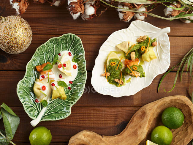 Верхний вид листовидных тарелок с вкусными равиоли, подаваемых с соусом песто — стоковое фото