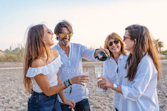 Веселі зрілі батьки та молоді дочки смердять келихами вина та сміються під час святкування возз'єднання сім'ї ввечері на курорті — стокове фото