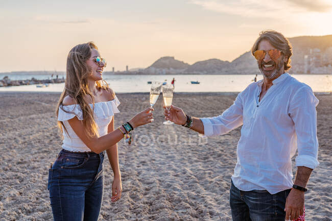 Vater und kleine Tochter klappern Weingläser und lachen, während sie am Abend im Resort ein Familientreffen feiern — Stockfoto