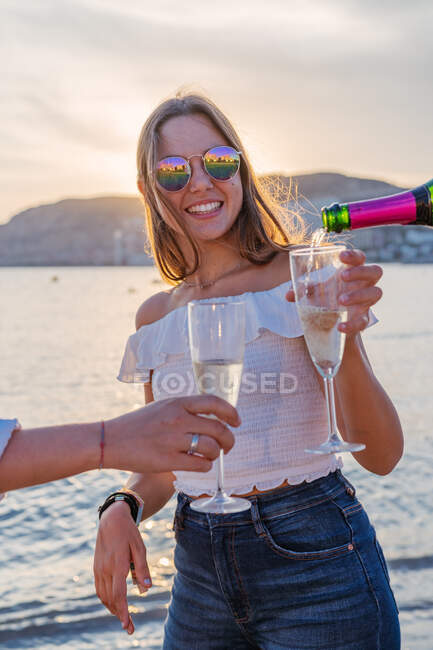 Allegro genitori maturi e giovani figlie clinking bicchieri di vino e ridere mentre si celebra riunione di famiglia in serata sul resort — Foto stock