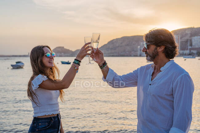 Vater und kleine Tochter klappern Weingläser und lachen, während sie am Abend im Resort ein Familientreffen feiern — Stockfoto