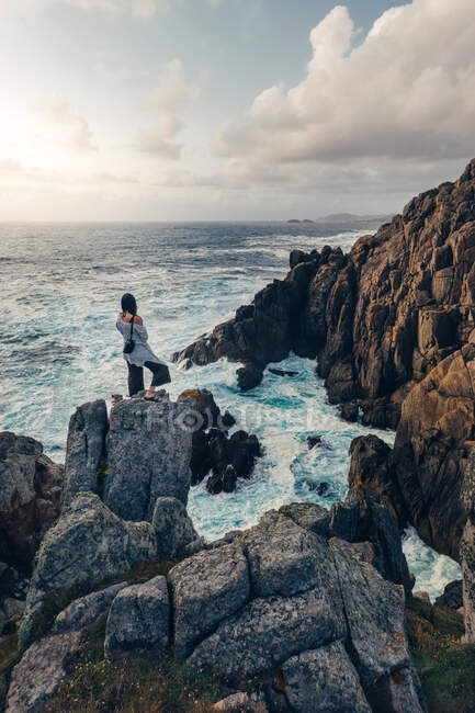 Mujer mirando rocas a la orilla del mar - foto de stock