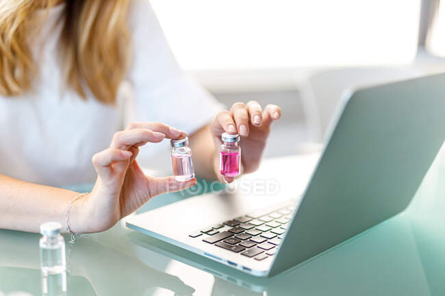 Femme travaillant à l'ordinateur portable avec des flacons médicaux — Photo de stock