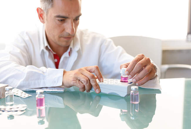 Assistant travaillant en laboratoire avec du liquide rose — Photo de stock