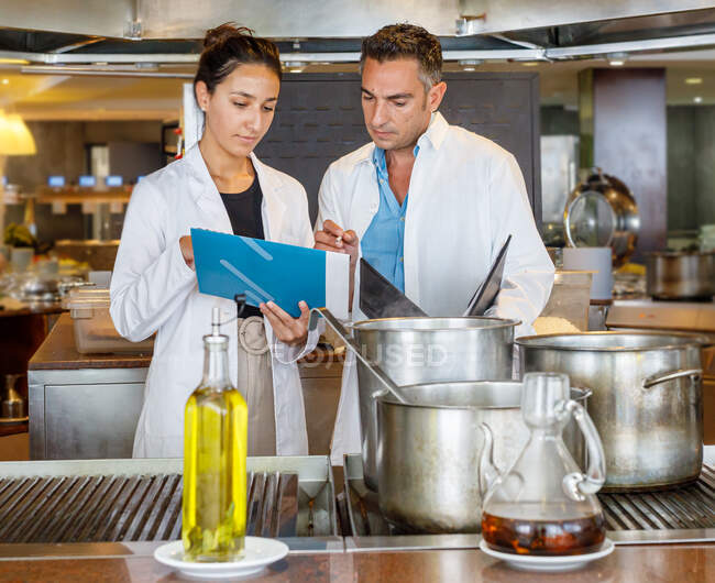 Coworkers verifica i risultati durante il test della qualità degli alimenti in cucina mensa — Foto stock