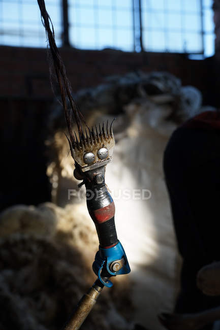 Rasoir professionnel de tonte des moutons suspendu à la corde dans une grange sombre à la ferme — Photo de stock