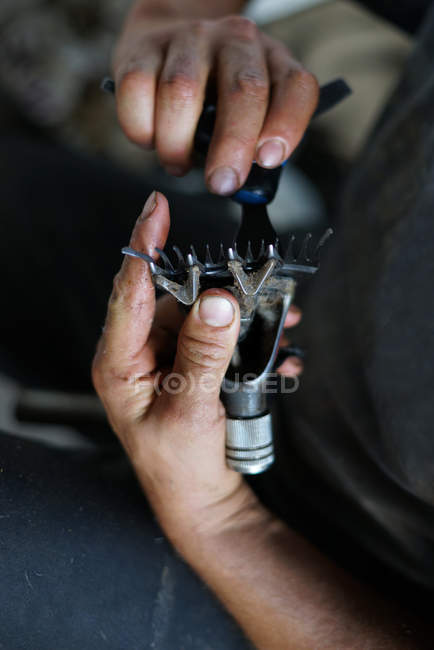 Geschnittenes Bild eines Mannes, der während der Arbeit in einer Scheune auf einem Bauernhof ein schmutziges Rasiermesser repariert — Stockfoto