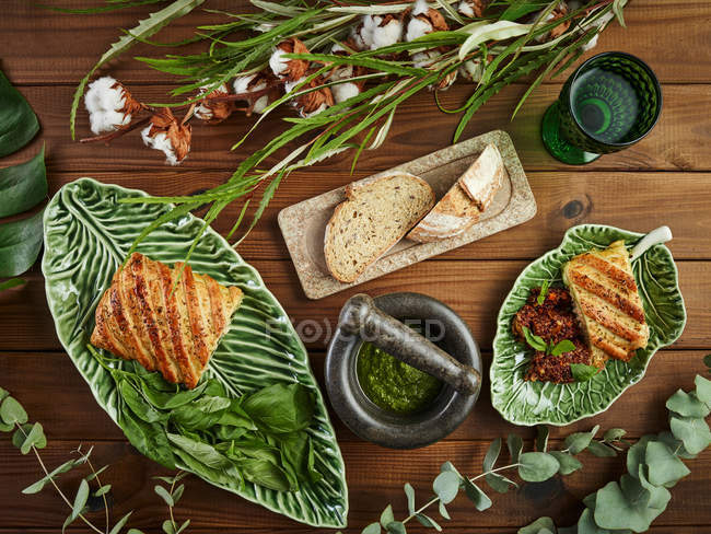 Blick von oben auf köstlichen Blätterteig mit Mozzarella und Lachs, serviert auf Tellern in der Nähe von Pesto-Sauce und Brot — Stockfoto
