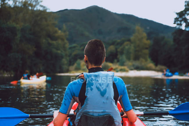 Back view of sportswoman padding in red canoe on Sella river in Spain — Stock Photo