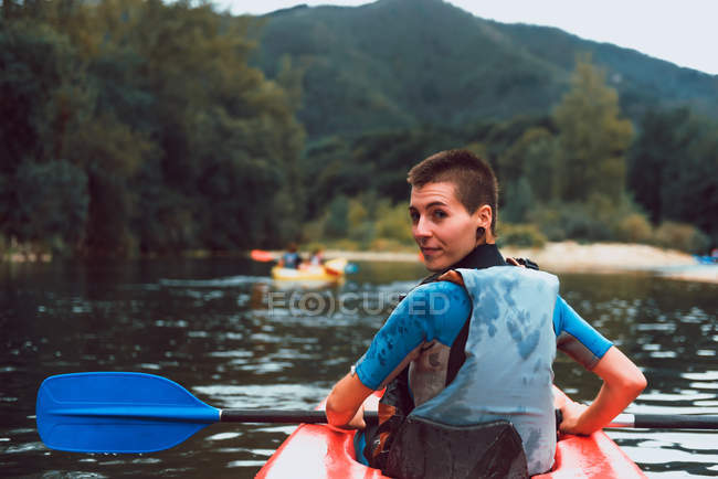 Назад вид спортсменки дивлячись на плече, а оббивка в червоному каное на Селла річки в Іспанії — стокове фото