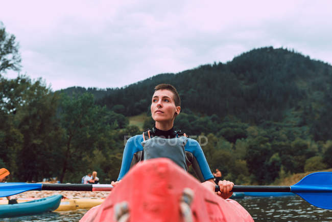 Sportive молода жінка з коротким волоссям сидячи в червоному каное і веслування на річці Селла спад в Іспанії — стокове фото
