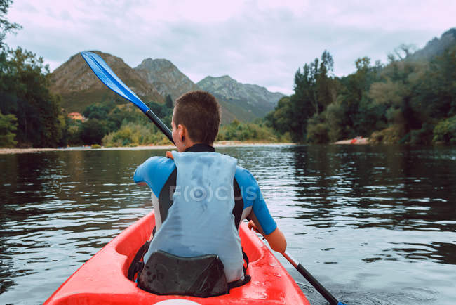 Visão traseira da jovem mulher desportiva estofando em canoa vermelha no rio Sella, na Espanha — Fotografia de Stock