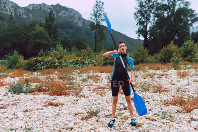 Donna sportiva in formazione muta con pagaia mentre in piedi sulla riva del fiume Sella in Spagna — Foto stock