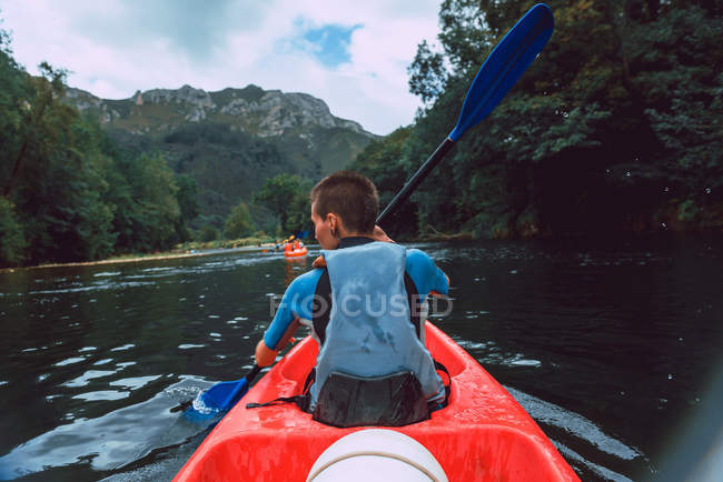 Vista posterior del acolchado de la deportista en canoa roja en el río Sella en España - foto de stock