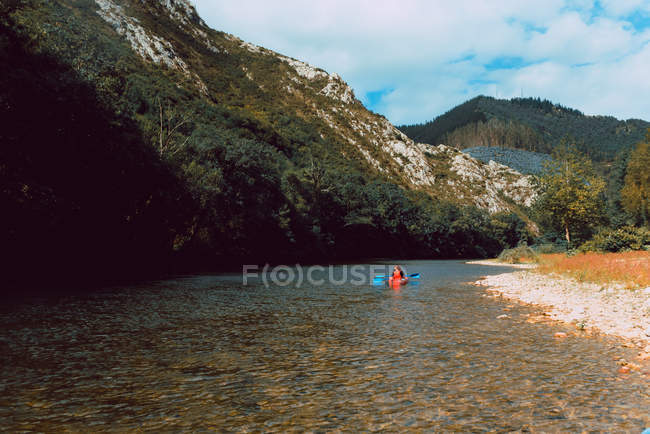 Distant back view of sportswoman padding in red canoe on Sella river in Spain — Stock Photo