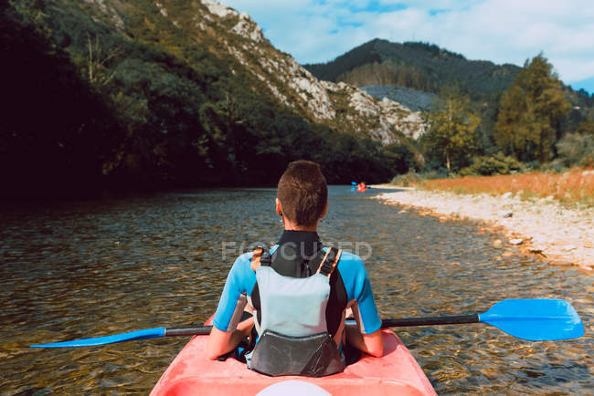 Back view of sportswoman padding in red canoe on Sella river in Spain — Stock Photo