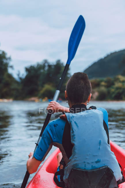 Vista posteriore del kayaker femminile con imbottitura per capelli corti sul declino del fiume Sella in Spagna — Foto stock