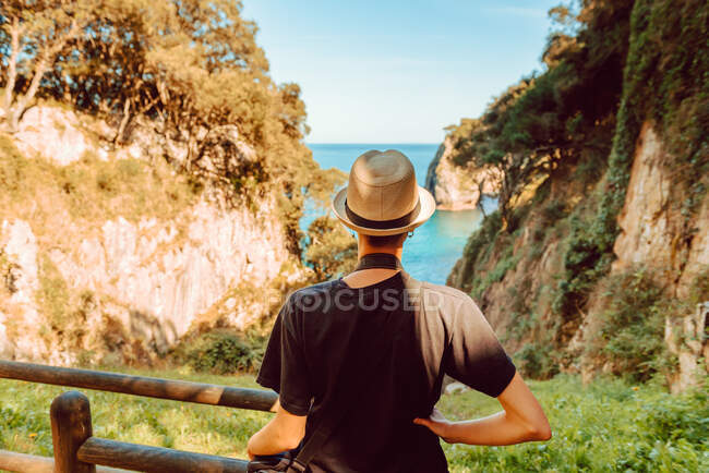Visão traseira da mulher de chapéu em pé por trilhos de madeira e desfrutando de uma vista deslumbrante do mar e falésias em Ribadedeva Astúrias Espanha — Fotografia de Stock
