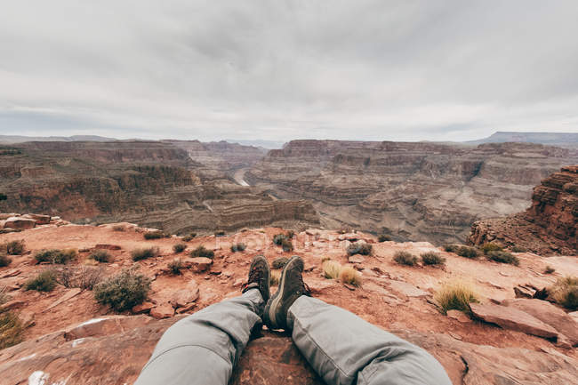 Cropped view of legs of man recreating on edge of cliffs at scenic canyon in USA — Stock Photo