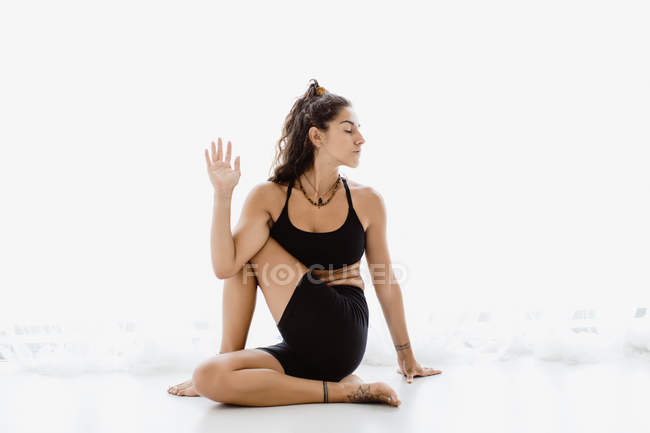 Sportive woman performing twisting yoga pose in studio — Stock Photo