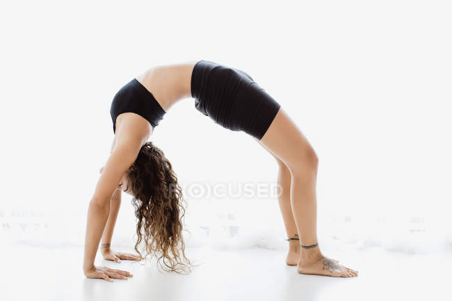 Sportive woman performing bridge yoga pose in studio — Stock Photo