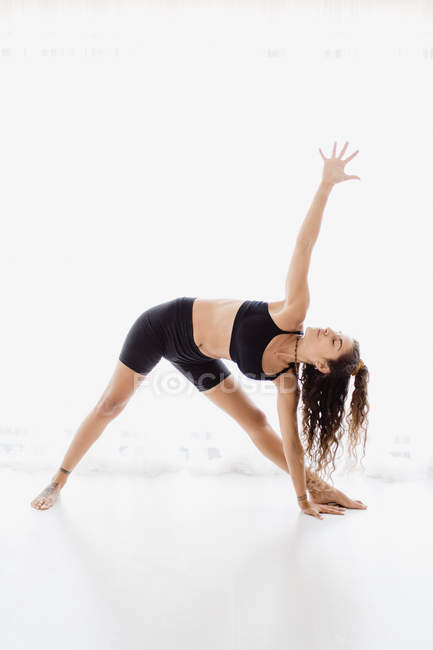 Sportive woman performing triangle yoga pose in studio — Stock Photo