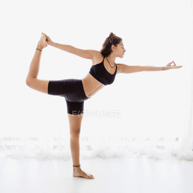 Молода жінка, виконуючи розтяжку йоги позу в студії — стокове фото