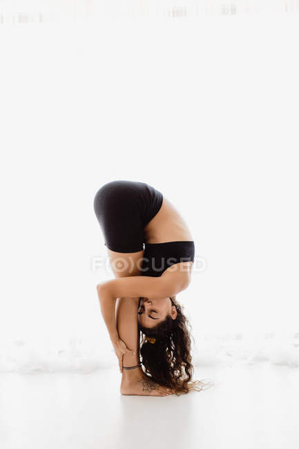 Sportive woman performing bending yoga pose in studio — Stock Photo