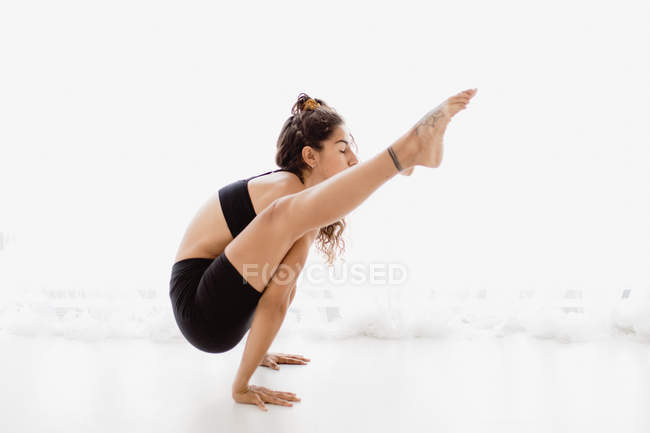 Young woman performing handstand yoga pose in studio — Stock Photo