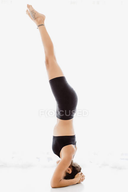 Side view of peaceful woman doing shirshasana pose over white background — Stock Photo