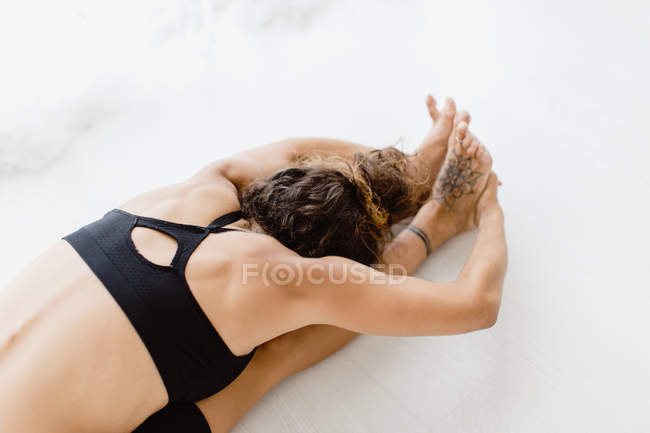Vista de ángulo alto de la mujer en forma que realiza la postura del yoga de flexión en el estudio - foto de stock
