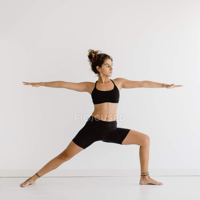 Fit woman performing warrior yoga pose in studio — Stock Photo