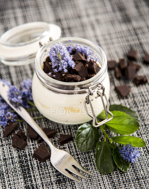 Bowl of fresh healthy yogurt with dark chocolate on gray napkin on table — Stock Photo