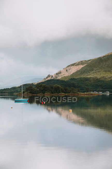 Paysage pittoresque de montagne et ciel nuageux reflété dans des eaux tranquilles avec des voiliers à Glencoe le jour — Photo de stock