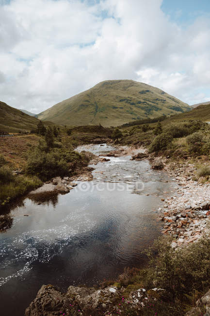 Picturesque landscape of mountain and cloudy sky reflected in tranquil water in Glencoe on daytime — Stock Photo