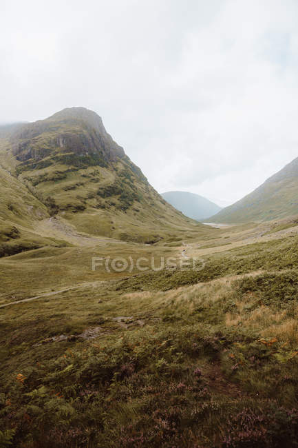 Vue pittoresque de la vallée verdoyante par de hautes roches à Glencoe le jour — Photo de stock
